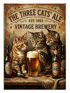 "The Three Cats Ale" yazılı masada oturan kediler.