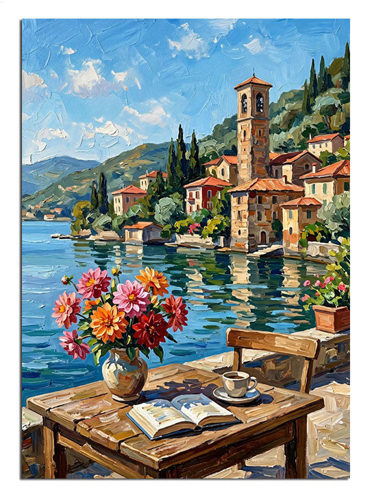 Göl kenarında kitap ve çiçek vazolu masa ve köy manzarası tablosu.